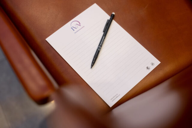 Ett linjerat papper med IVA Konferenscenterloggan på och en penna som ligger tvärs över.