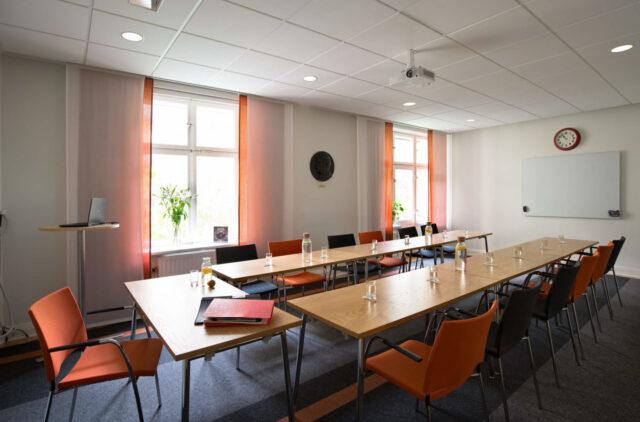 Konferenslokal möblerad i en U-form med öppningen mot en whiteboard.