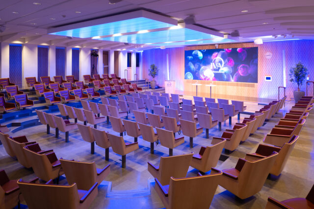 Konferenslokal med stolarna ställda i teaterstil där stolarna står i ett kluster och är riktade mot scenen.